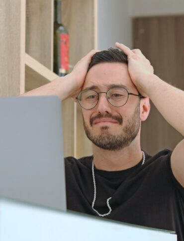 a man with glasses is looking at a laptop